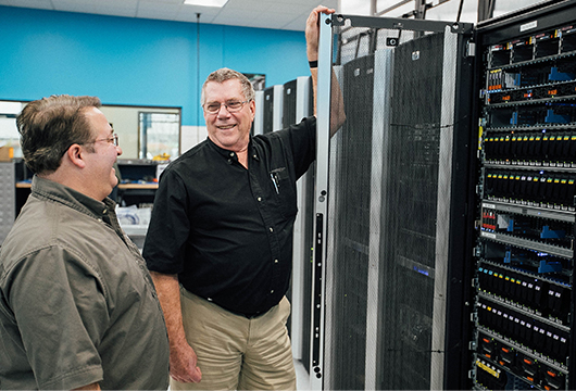 Two Engineers Laugh Near Open Server Door