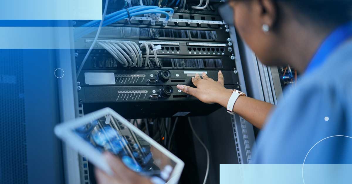 An image of a female engineer holding a tablet and reaching into a server rack to inspect equipment