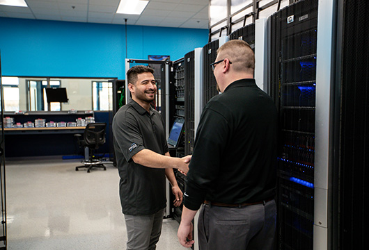 An image of two male engineers shaking hands in a data center