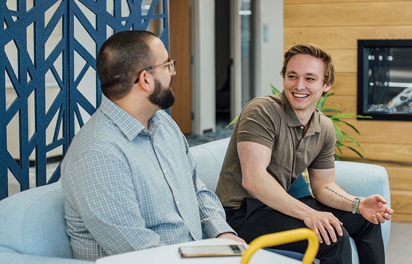 An image of two male Service Express employees sitting on a couch, smiling, and having a conversation