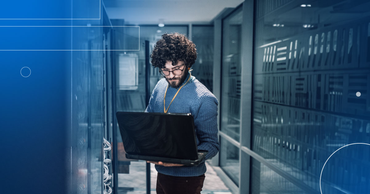 An image of a male engineer holding a laptop in a data center