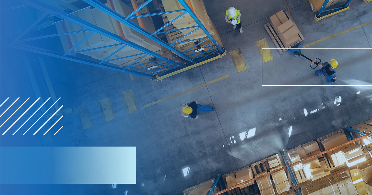 An overhead shot of a warehouse floor with workers in hardhats doing their tasks