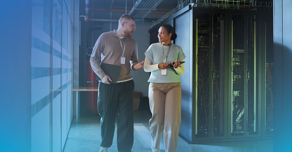An image of a male and female engineer having a conversation while walking through a data center