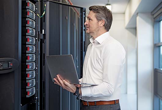 Engineer Holding Laptop Troubleshooting Data Centre Equipment