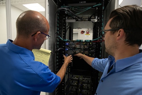 Two Engineers Reaching into Server