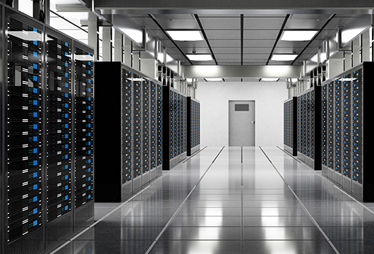 Wide shot of a pristine-looking data center with servers lining the tiled walkway and a door at the end of the room.