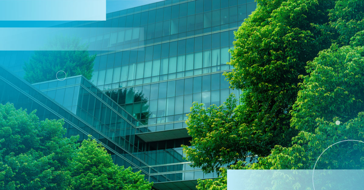 An image of lush trees in front of a building with large glass windows