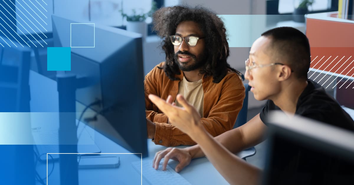 An image of two people in front of a computer analyzing what is on the monitor