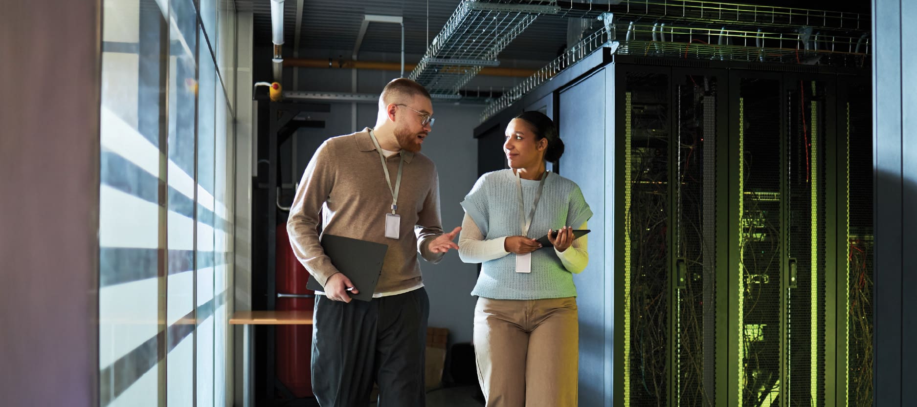 An image of a male and female engineer having a conversation about IBM consulting services while walking through a data center