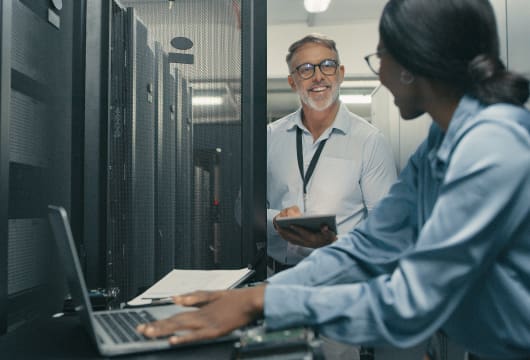 An image of two IT professionals having a chat in a data center